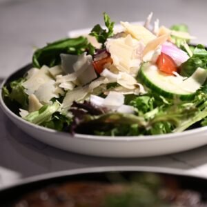 A white bowl filled with a salad on top of a table
